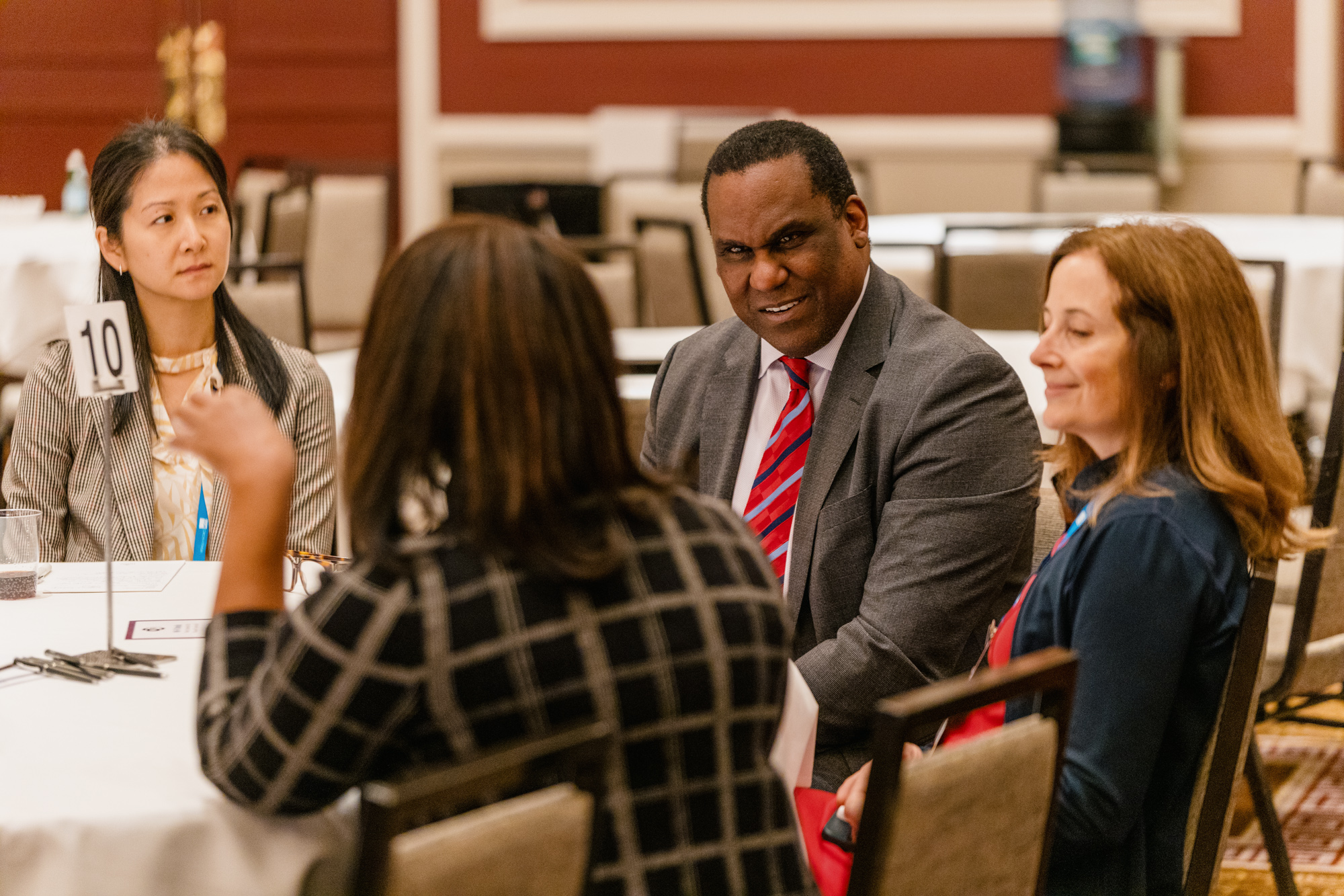 One man and three women having a conversation at a table during a conference